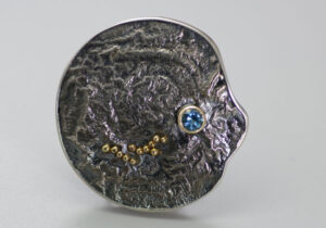 BRPN-3-Oxidized reticulated silver, 22k, 14k gold, blue topaz. Brooch may be worn as a pendant. 1.75 inches.
