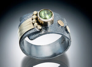 R–20: Peridot 5mm set in 18k gold, with 22k gold fused balls, on oxidized sterling silver. Size 8.0. $950.00 